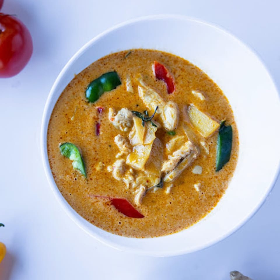 TG Thai Food's red curry with chicken, bamboo shoots, and peppers in a white bowl.