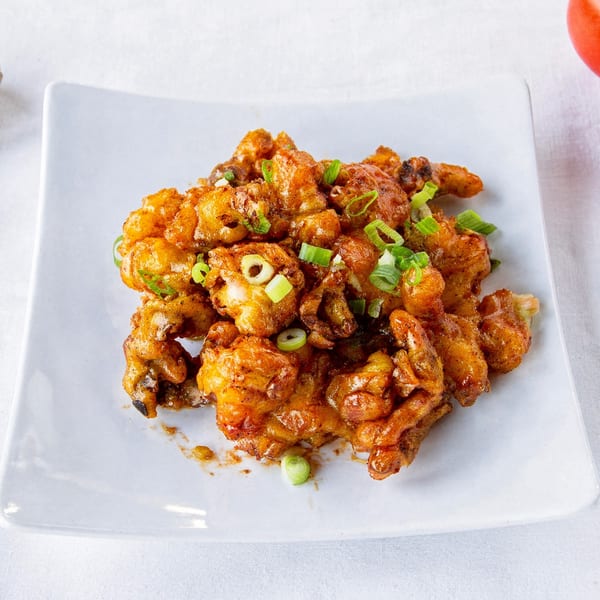 TG Thai Food's crispy fried chicken pieces, glazed with sauce and garnished with green onions.