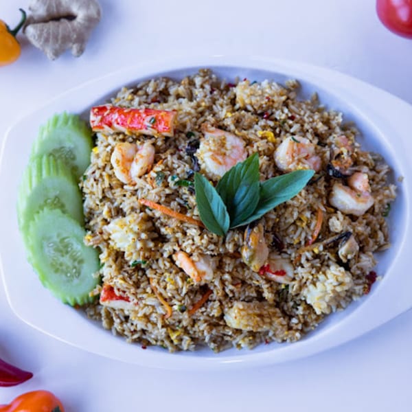 TG Thai Food's seafood fried rice with shrimp, crab, mussels, and basil, garnished with cucumber slices.