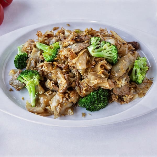 TG Thai Food's Pad See Ew with wide noodles, meat, and broccoli on a white plate.