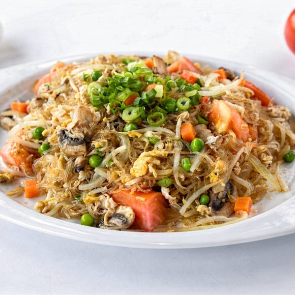 A plate of Thai glass noodles with vegetables, mushrooms, and scrambled egg, garnished with green onions.